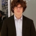 J.D. Porter in a white shirt and dark jacket standing in front of a glass wall. 