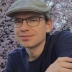 Jared Farmer in a dark shirt and grey cap standing in front of a cherry tree