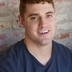 Matt Aiello in a dark t shirt in front of a brick wall