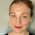 Prof. Nicky Agate in a black shirt and gold hoop earings
