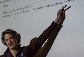 Instructor pointing a marker at a projected image of code on a screen