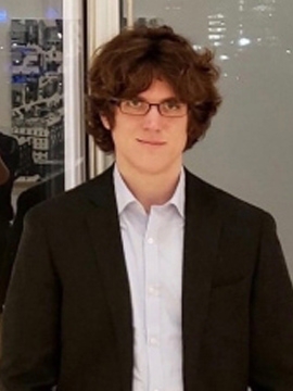 J.D. Porter in a white shirt and dark jacket standing in front of a glass wall.
