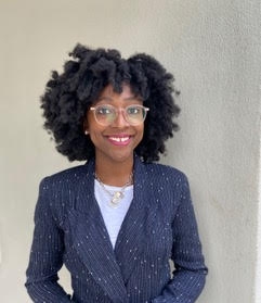 Kelcey Gibbons standing in front of a gray wall